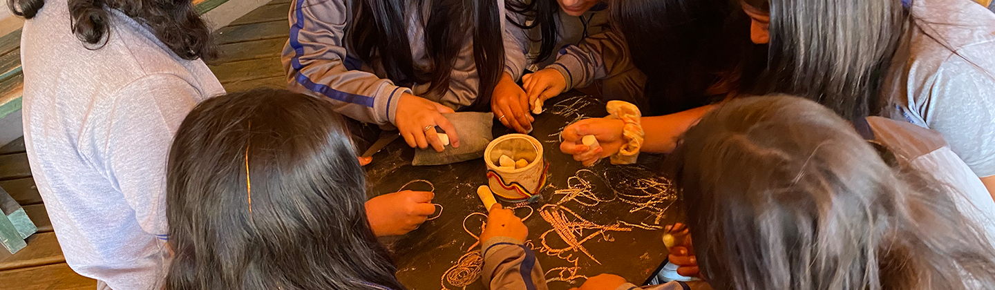 niños dibujando en las mesas de pizarra del parque rupestre